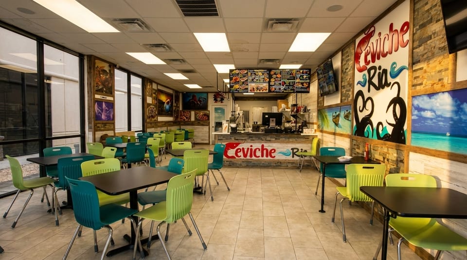 Interior of Ceviche Ria restaurant with empty tables, colorful chairs, and a counter with menus.