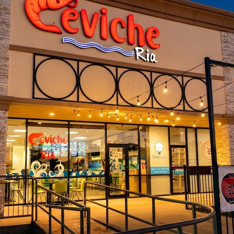 Exterior of Ceviche Ria restaurant at dusk, with a "WE ARE OPEN" banner and string lights.